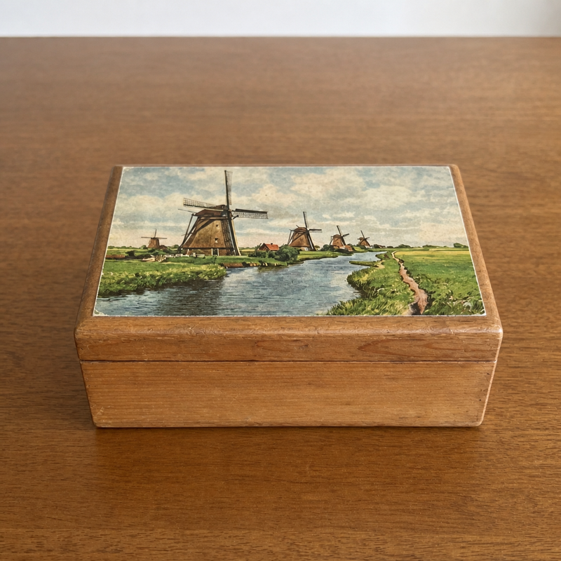 A vintage cedar keepsake box with a Dutch windmill scene on the lid, photographed on a warm wood table